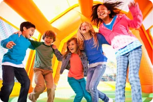A group of kids bouncing on a inflatable bounce house have fun times.