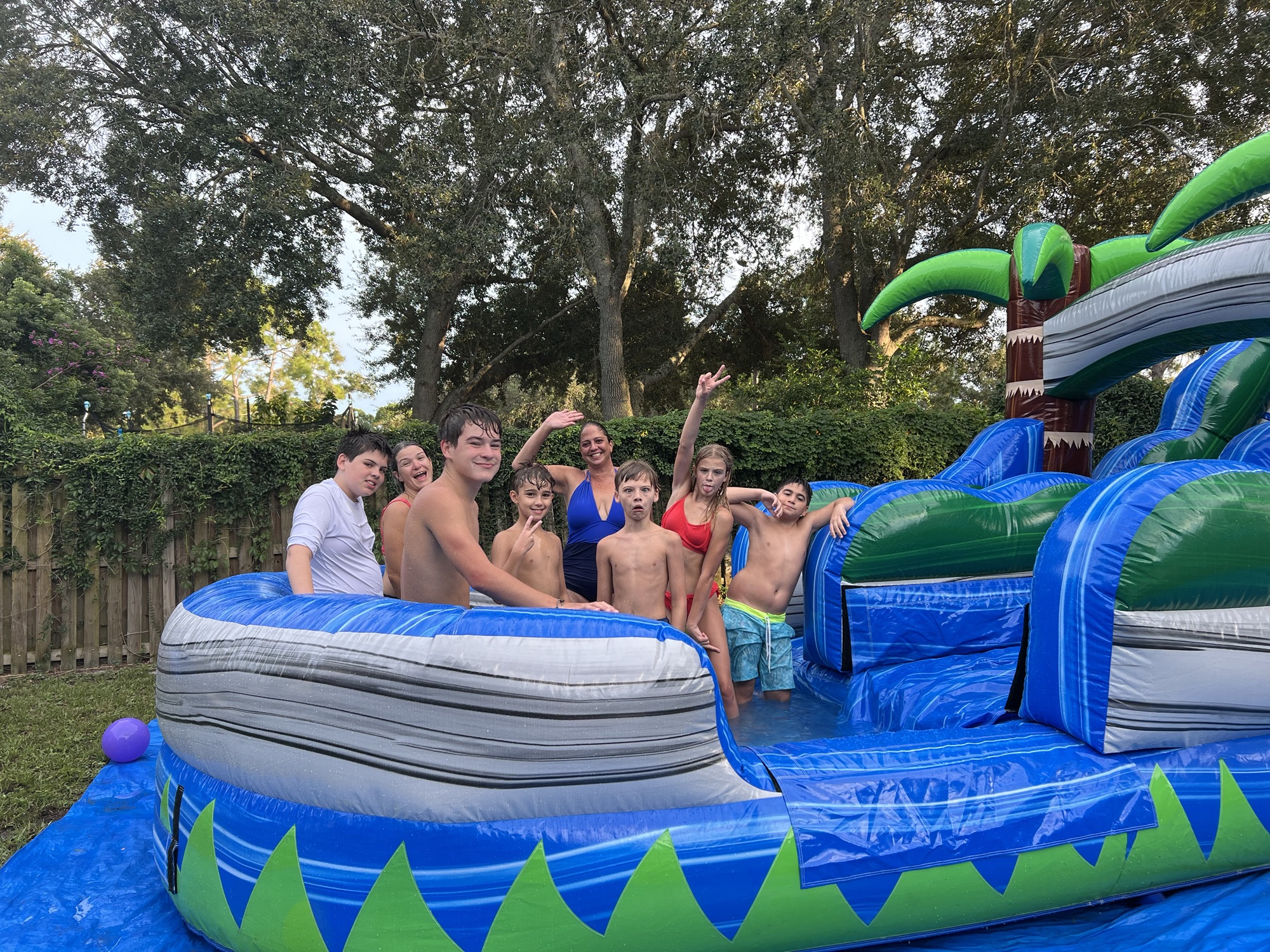 A group of cheerful bunch of kids at the bottom of a waterslide.