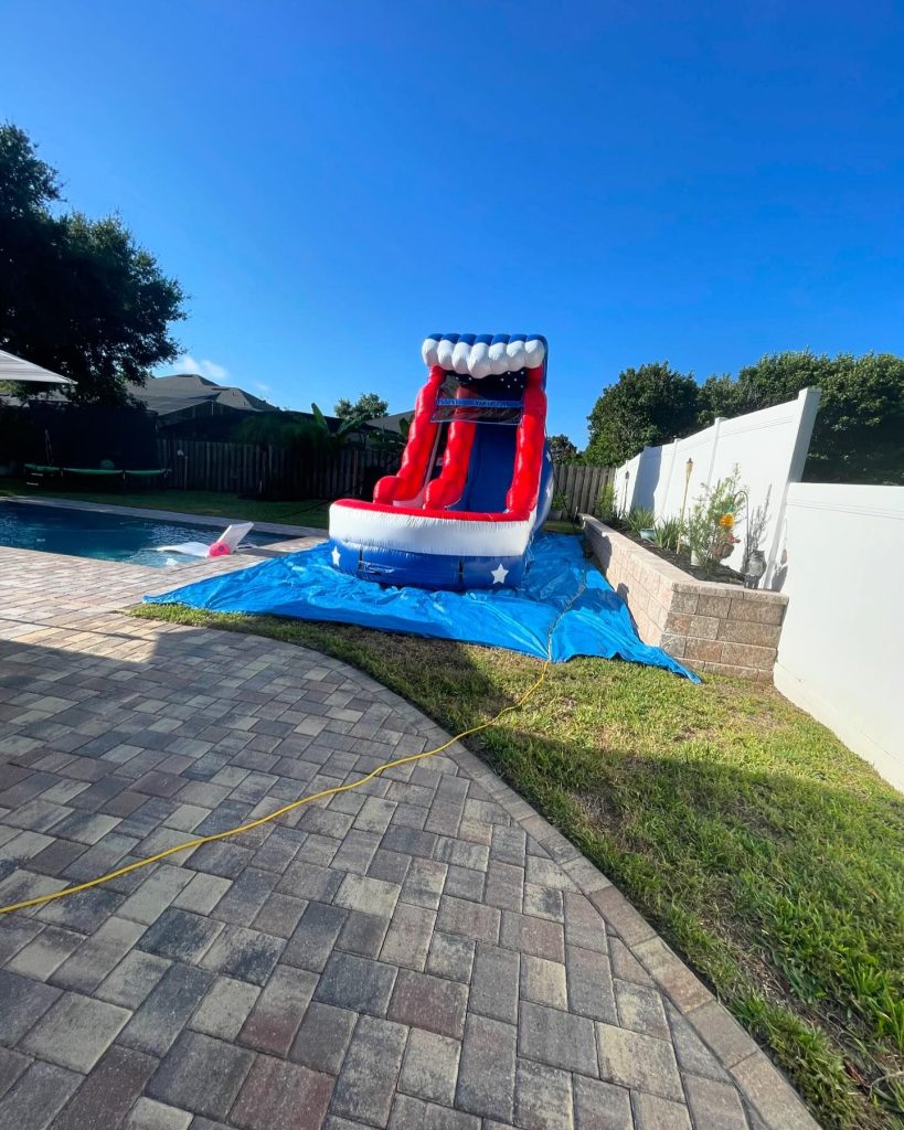 a red white a blue waterslide on a bule tarp placed outside