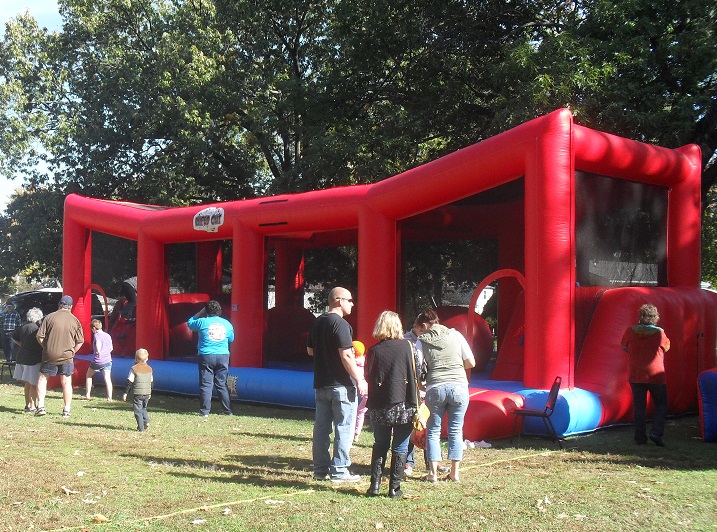 a red and bule inflatable outside with people standing around.